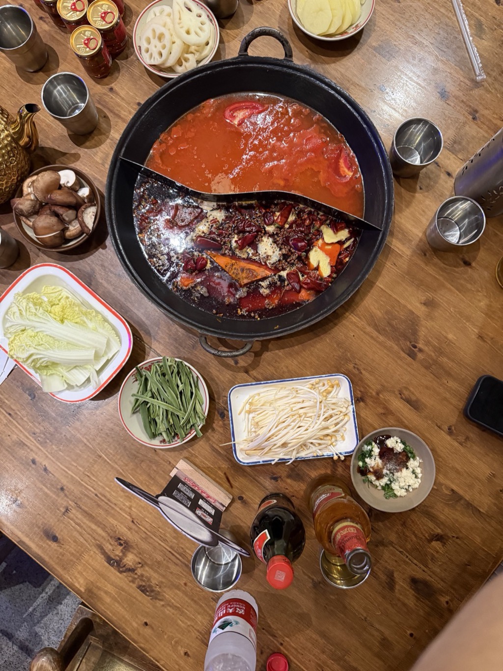 A Chongqing hotpot with a divided pot of spicy and mild broth, surrounded by side dishes.