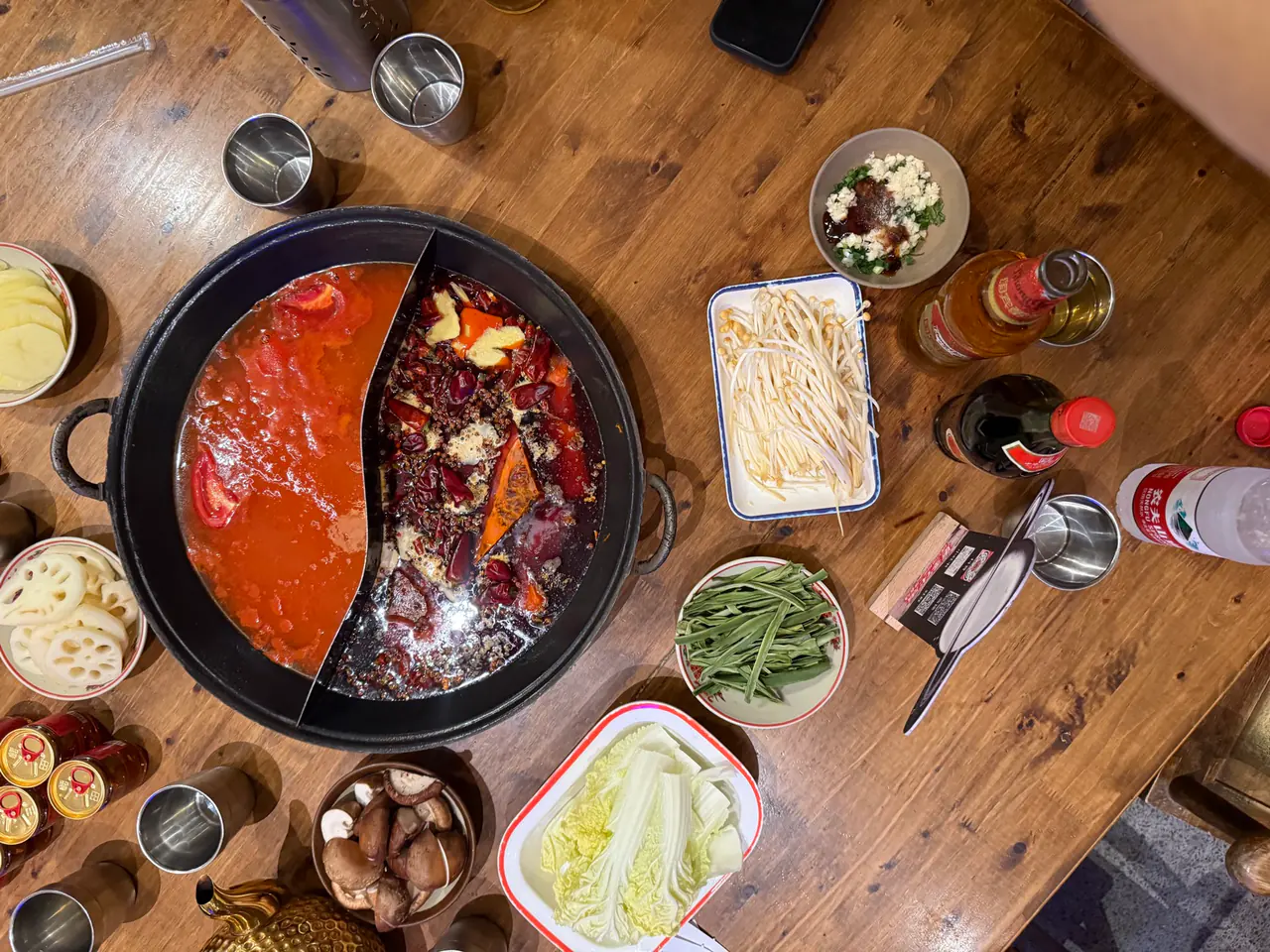 A Chongqing hotpot with a divided pot of spicy and mild broth, surrounded by side dishes.
